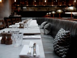 A comfortable, cushioned chair at a restaurant table with a clear drinking glass, sunlight softly illuminating the table setting, creating a warm and inviting dining atmosphere