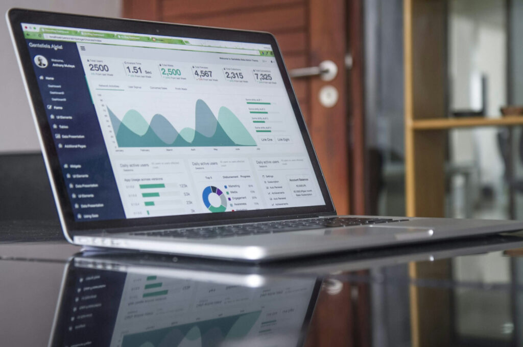 A laptop on a desk displays analytics with graphs and charts. The scene is set in a modern office, conveying a professional and analytical tone.