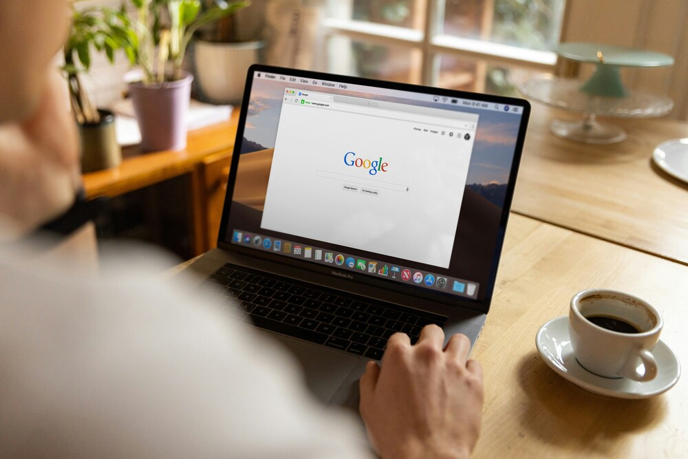 A man seated at a desk looking at a laptop screen open on Google, suggesting online research, information searching, or digital work in a focused environment