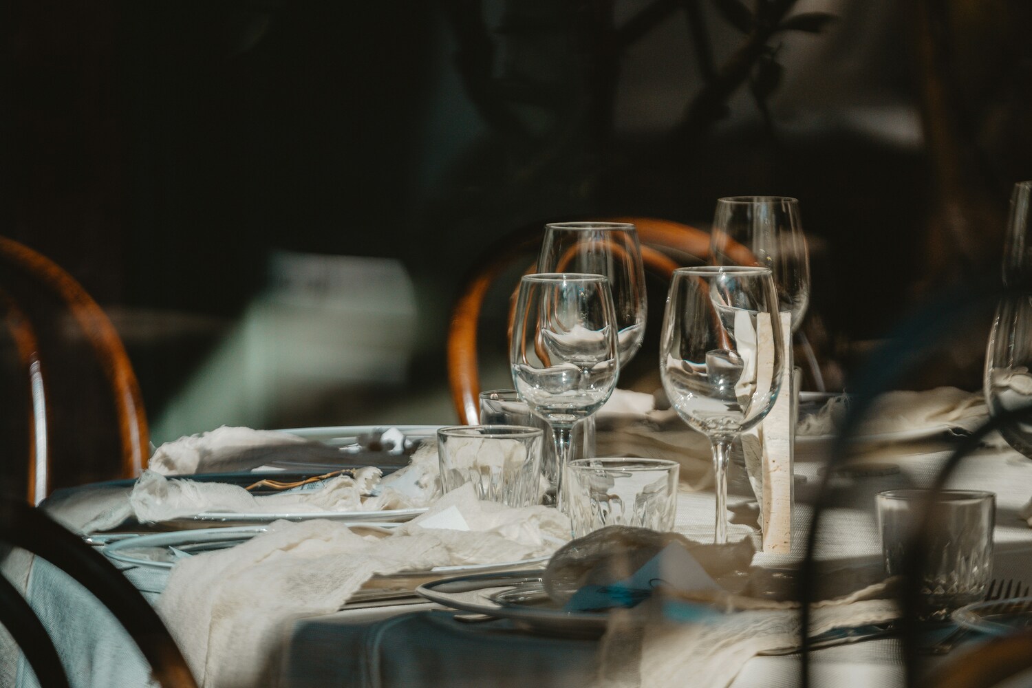 A neatly arranged set of clear glassware placed on a restaurant table, reflecting ambient light and creating a clean, elegant dining atmosphere.