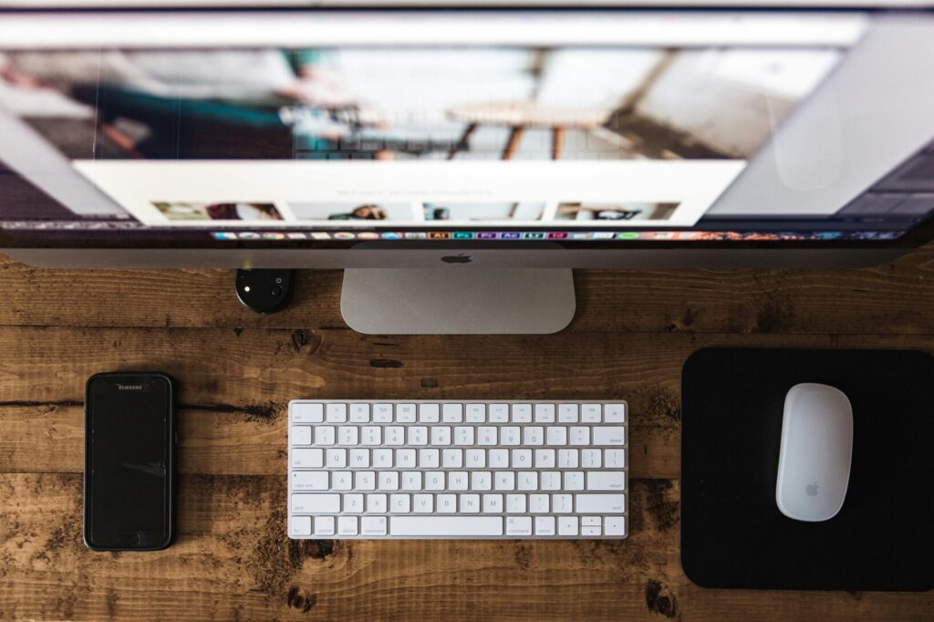Close-up view of a tidy work desk featuring a smartphone and computer mouse on a wooden table, representing a balanced digital workspace.