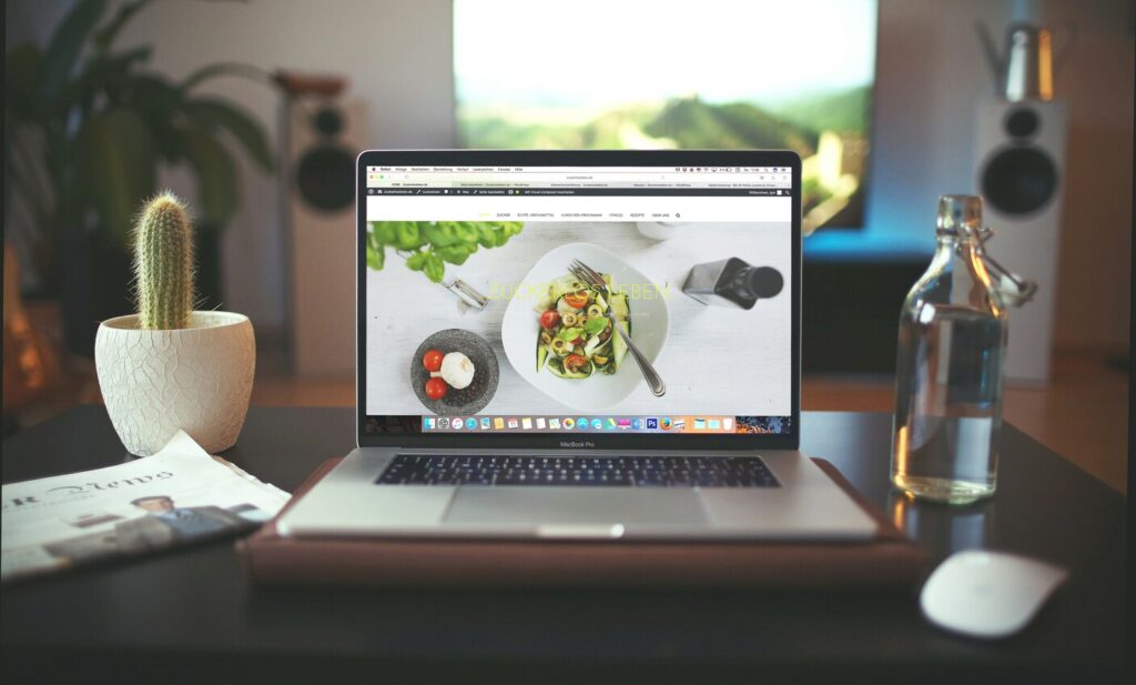 A laptop displaying a high-quality image of a food dish on the screen, suggesting digital menus, food content creation, or online marketing.
