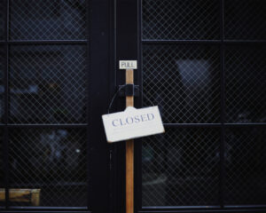 A “Closed” sign hanging on a restaurant door, symbolising a pause in operations or off-hours for the business.
