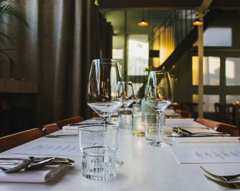 A neatly arranged glass and plate setting on a restaurant table, reflecting a clean and elegant dining atmosphere.