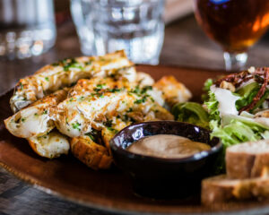 A beautifully plated dish served on a ceramic plate, presented with careful attention to colour, texture, and garnish in a softly lit restaurant setting.