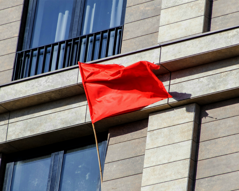 A red flag displayed outside a modern building, signalling attention or marking the location clearly from the street.