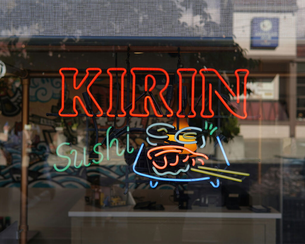Exterior sushi restaurant signage displayed at the entrance, featuring bold Japanese-style typography that welcomes guests into the dining space.