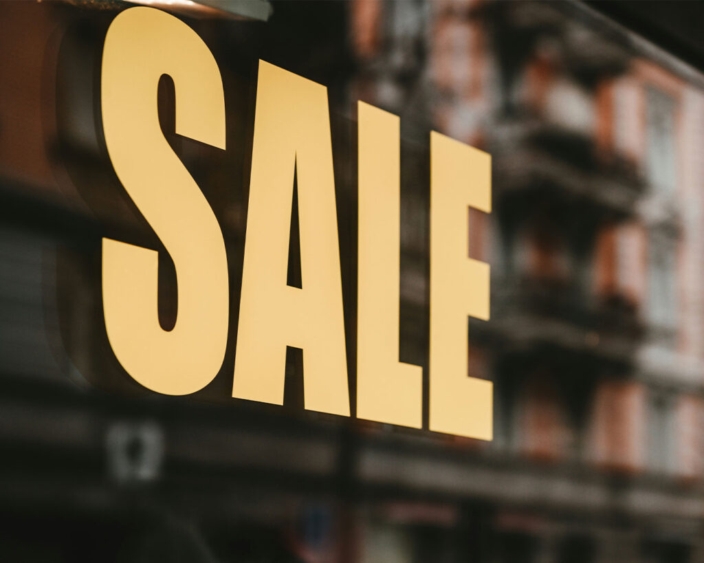Restaurant storefront window displaying a bold “Sale” sign, attracting attention from pedestrians outside.