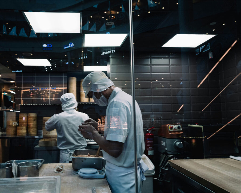 A busy restaurant kitchen with staff moving between stations, preparing meals in an active work setting.