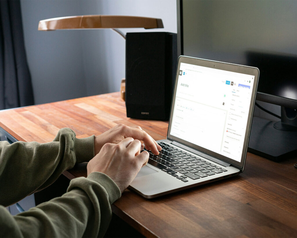 Man seated at a desk typing on a computer keyboard, focused on work in an office environment.