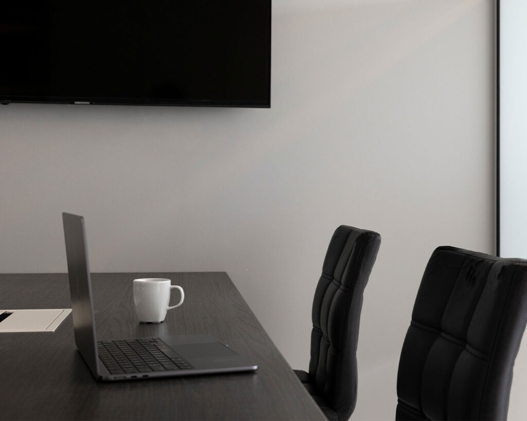 A laptop placed on a meeting room table, prepared for a presentation or discussion in a professional workspace.