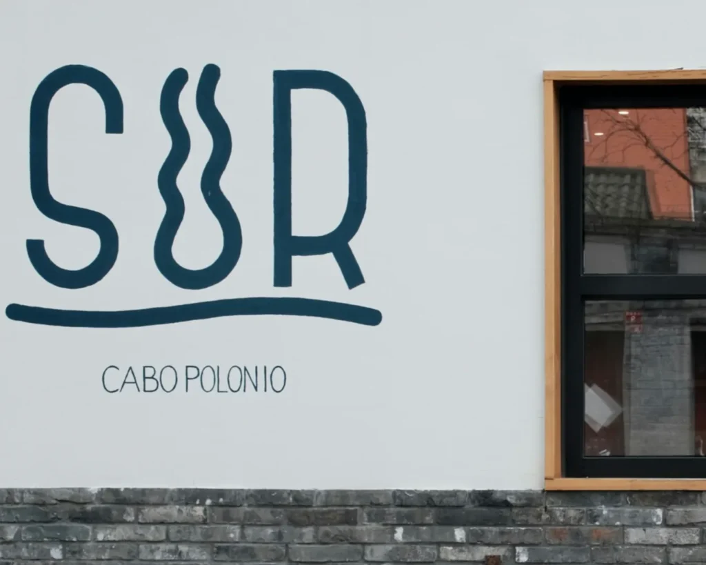 Wall with the word "SUR" in bold letters and "Cabo Polonio" beneath. Nearby window shows reflection and text, "Nuestro norte es el sur.