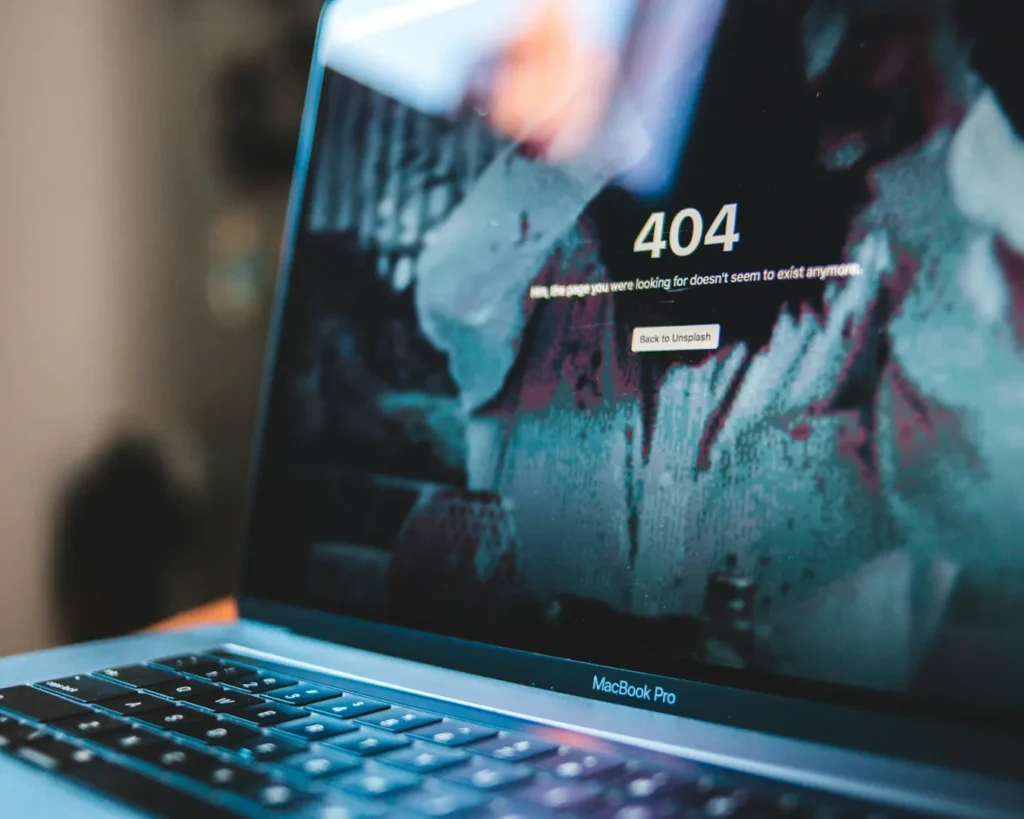 "Laptop displaying a "404" error message on screen. The background is blurred and abstract, creating a sense of confusion and inaccessibility."