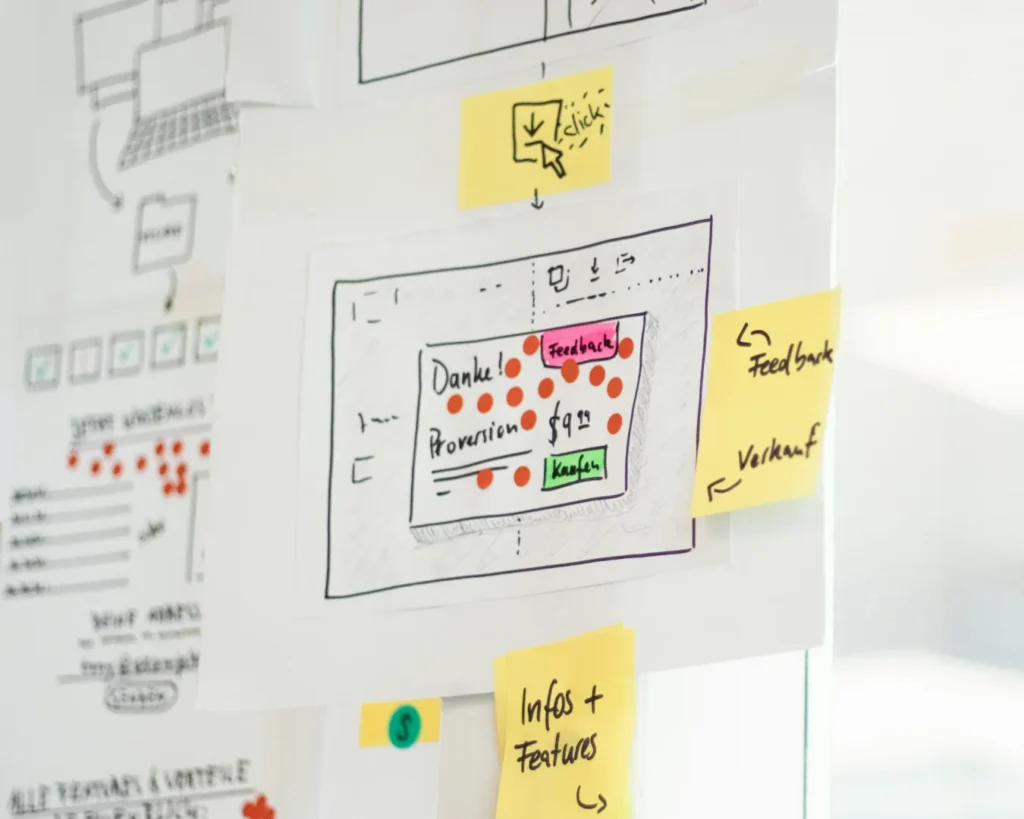 A storyboard with sketches and sticky notes, featuring an interface design with German text. Notes mention "Feedback" and "click," conveying a creative planning process.