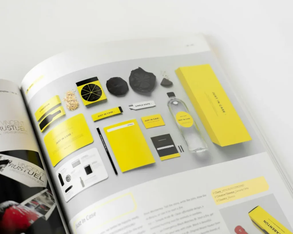A magazine spread features a vibrant yellow and black branding kit, including stationery, packaging, and a bottle, conveying modern and sleek design.