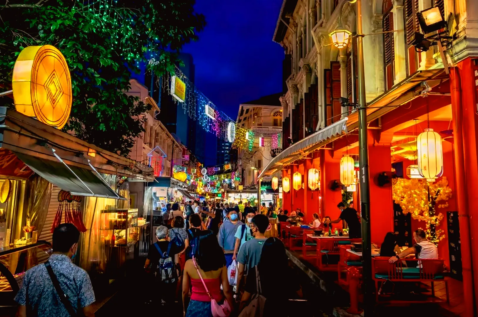 Busy nightlife dining street in Singapore with multiple restaurants and heavy foot traffic, showing strong competition in the F&B market