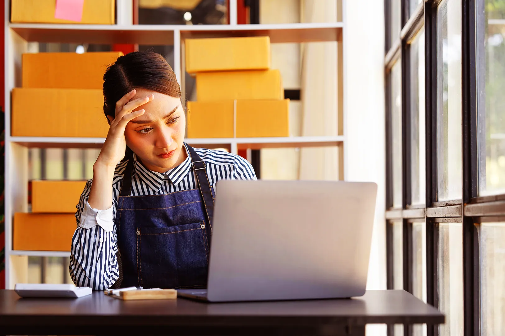 Restaurant owner in Singapore reviewing marketing work on laptop, showing stress caused by poor agency execution and hidden operational costs
