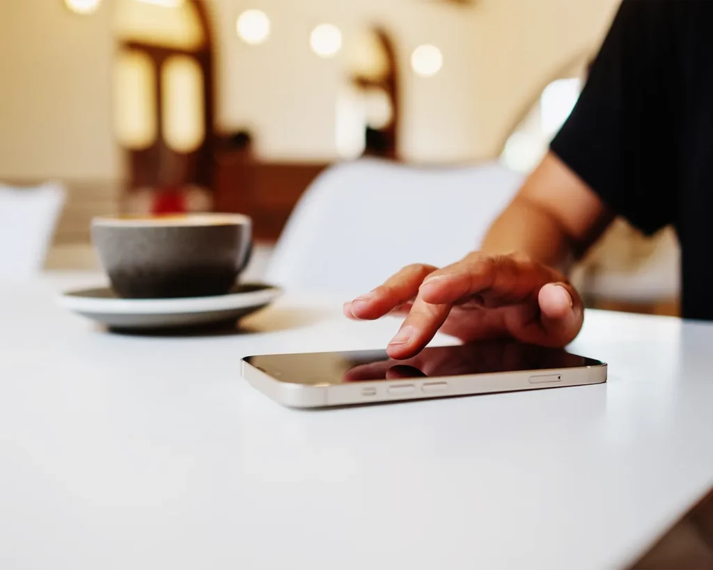 Customer using smartphone in a Singapore café to browse restaurant website, highlighting mobile user experience and ease of navigation
