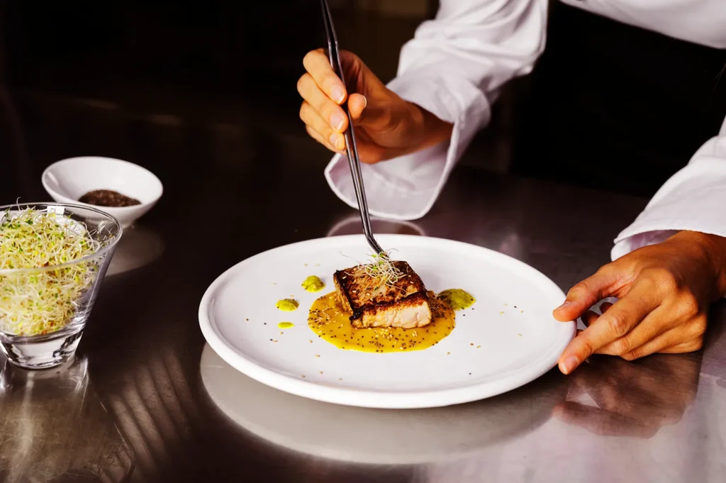 Chef in Singapore carefully plating a dish with precision, representing quality execution and expertise in restaurant branding and service