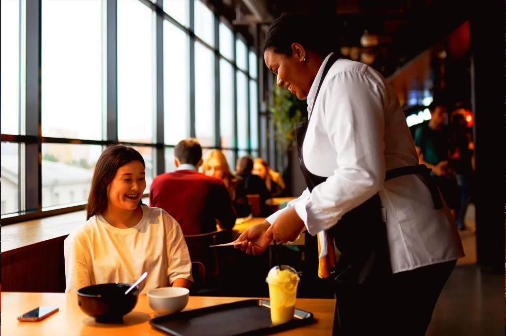 Restaurant staff in Singapore serving a guest with attentive service, demonstrating branding through customer experience and operations