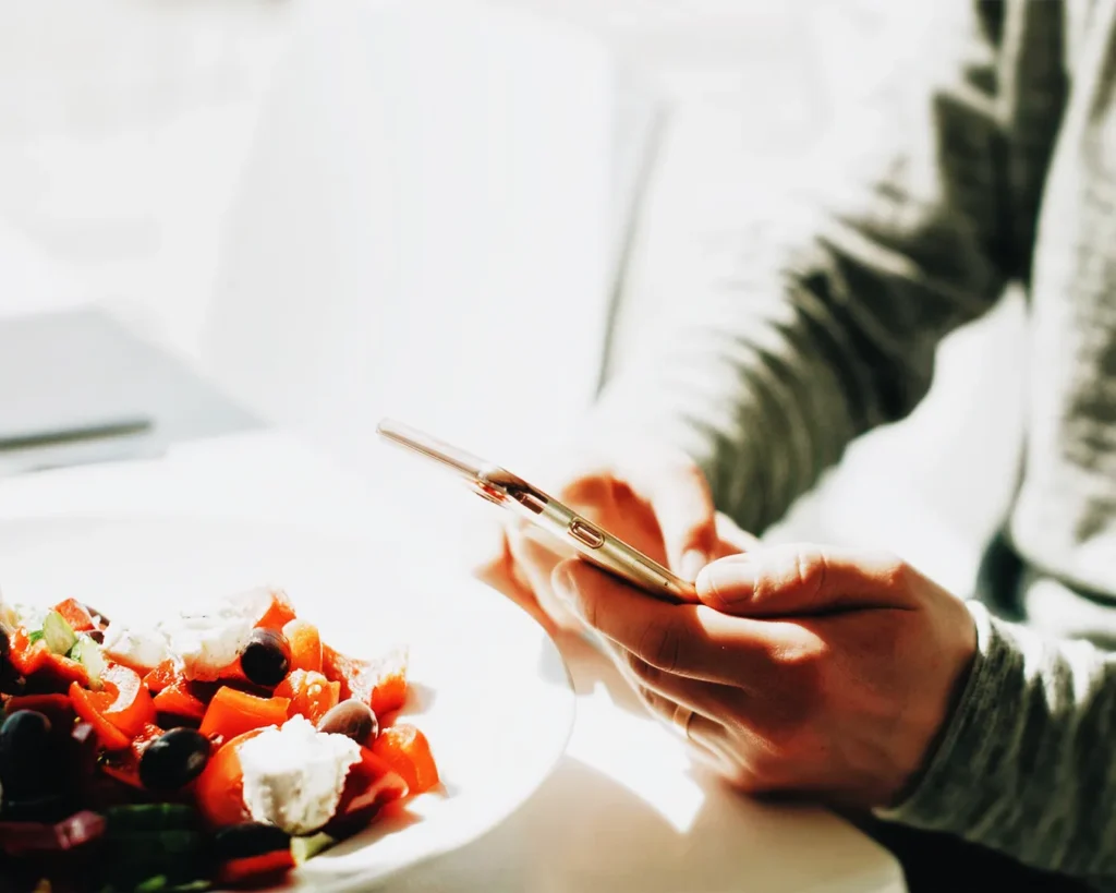 Customer checking restaurant details on smartphone while dining in Singapore, showing real-time mobile interaction with F&B brands