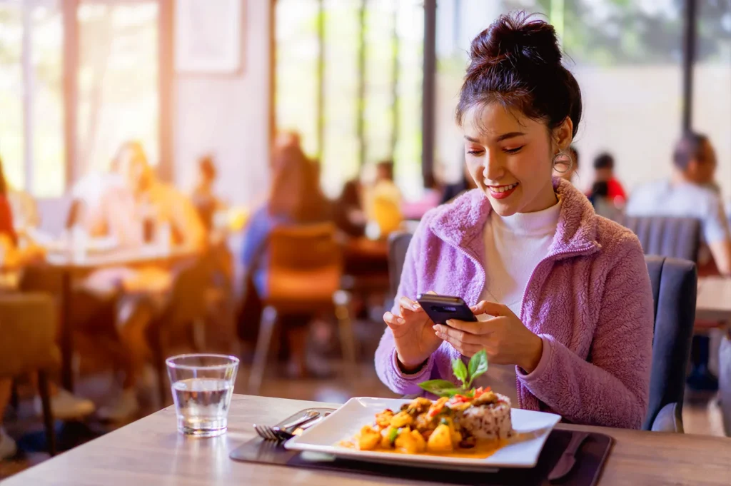 Restaurant guest in Singapore taking photo of meal with smartphone, reflecting social media marketing and visual storytelling in F&B