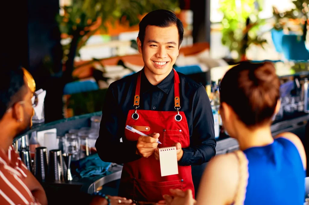 Restaurant staff in Singapore taking order and engaging with guests, showing customer experience and community-driven F&B marketing