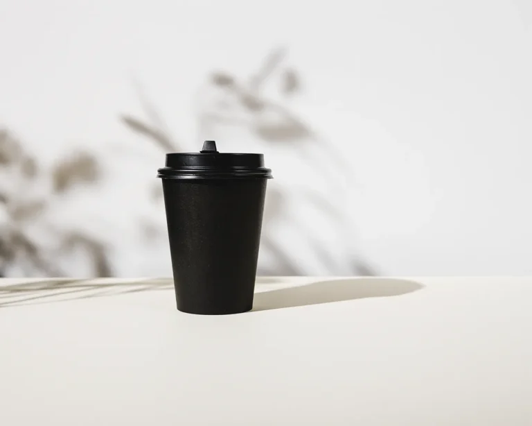 Minimalist black takeaway coffee cup on neutral background for modern restaurant rebranding and premium cafe brand identity