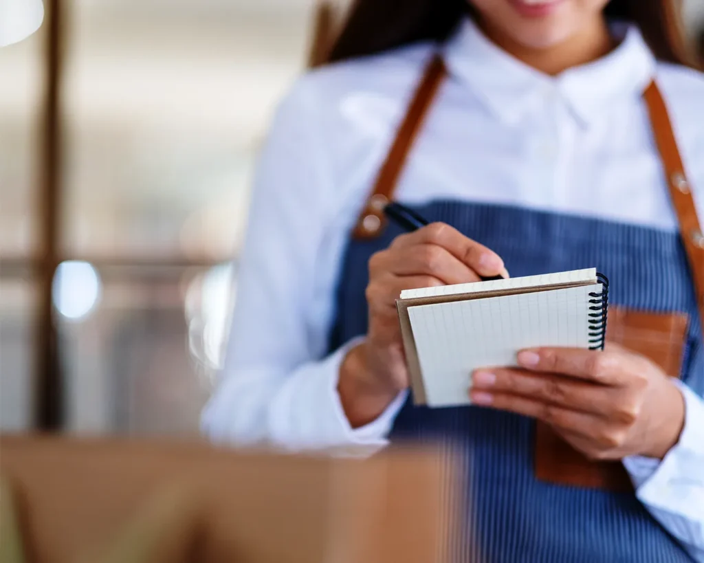 Restaurant staff writing notes during service, reflecting operational standards and structured brand guidelines in F&B