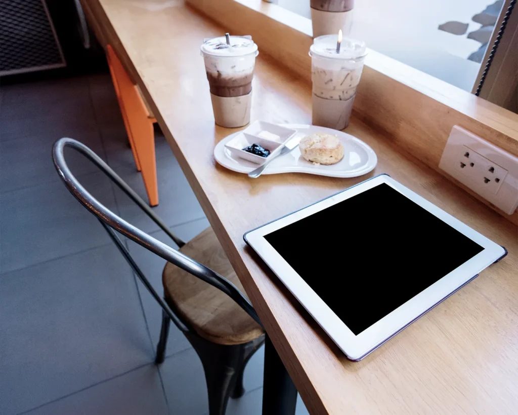 Tablet on café counter beside iced coffee drinks representing digital menu consistency and restaurant brand management after rebranding