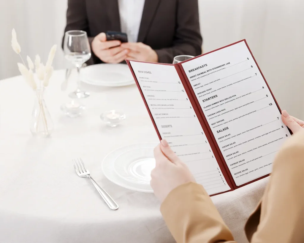 Restaurant guest reviewing a clean and organized menu layout in a modern dining space, highlighting effective menu design tips for restaurant owners