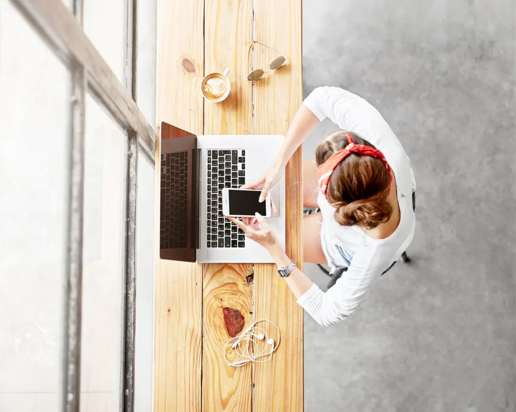 Overhead view of cafe workspace with laptop and smartphone for restaurant social media content scheduling