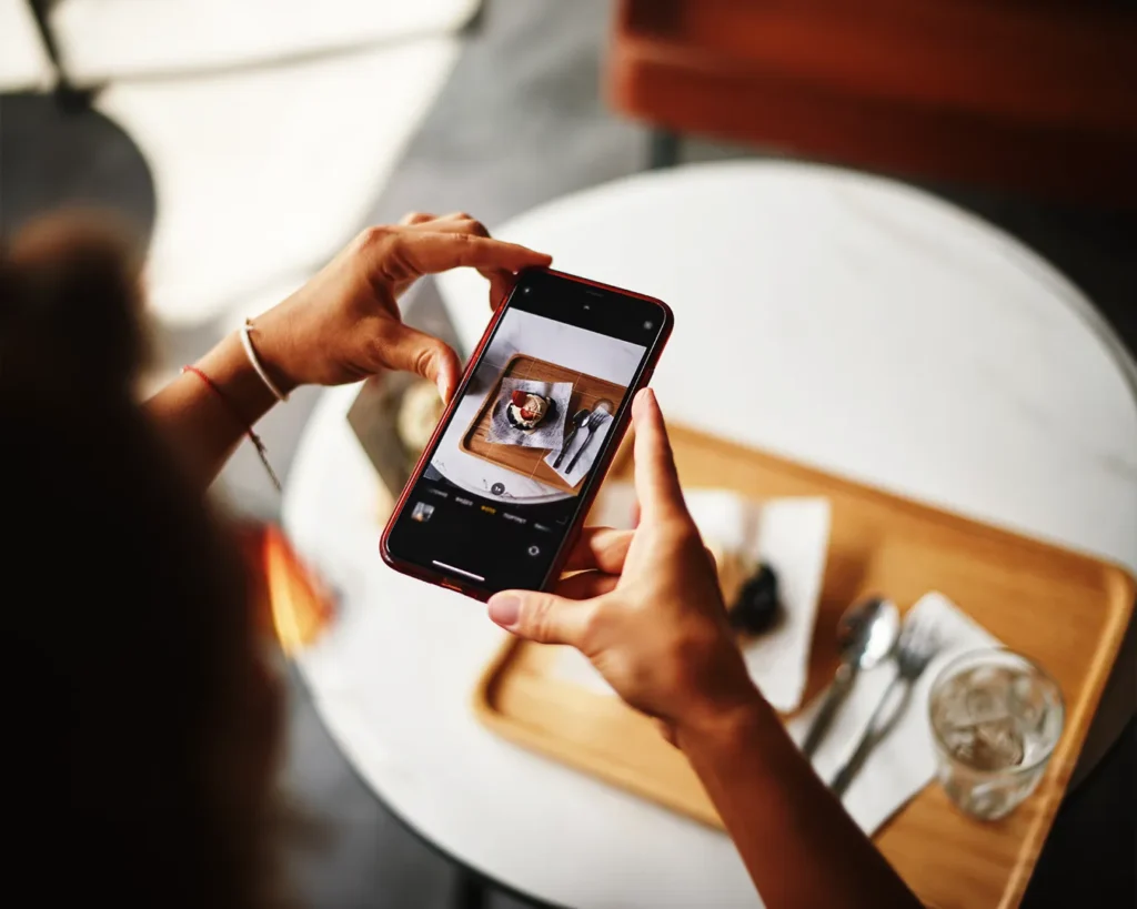 Customer photographing food in restaurant, highlighting digital presence and visual branding in Singapore F&B marketing