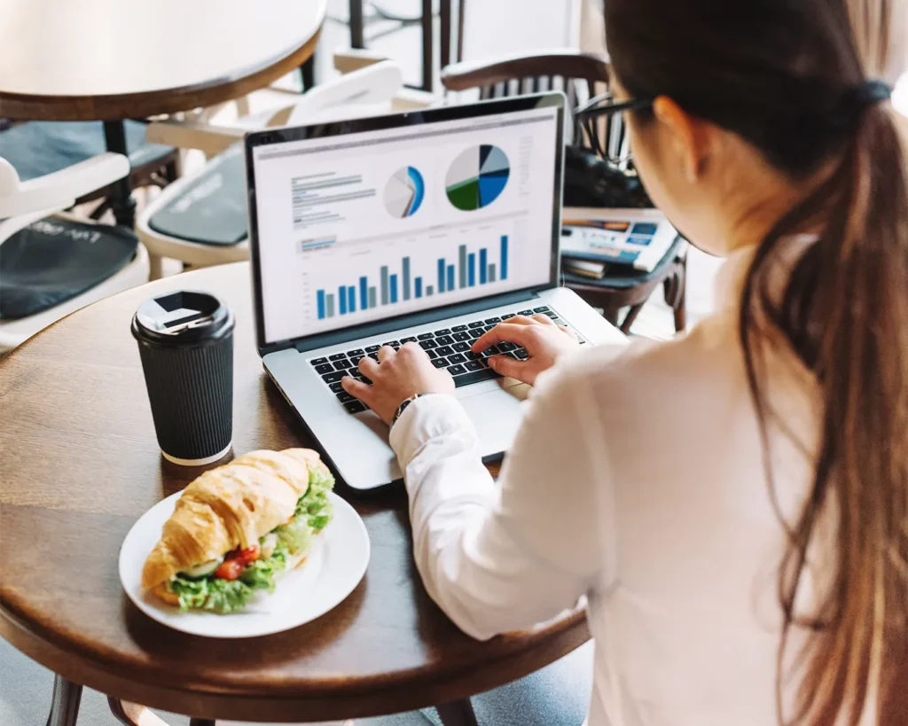 Restaurant owner reviewing marketing analytics on laptop inside café for local SEO and digital growth strategy