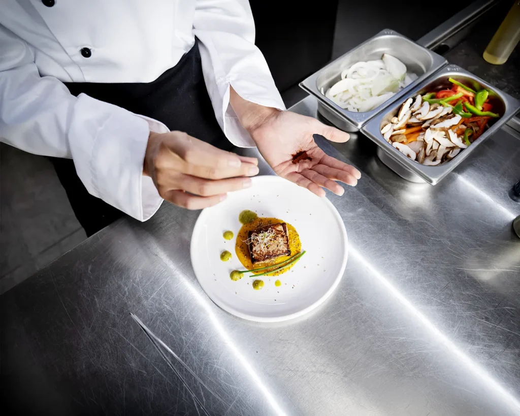 Chef plating premium restaurant dish in professional kitchen reflecting operational quality behind successful restaurant branding.