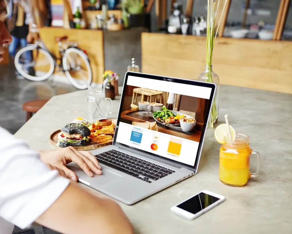 Modern restaurant website displayed on laptop beside gourmet burger and drinks for restaurant website branding concept