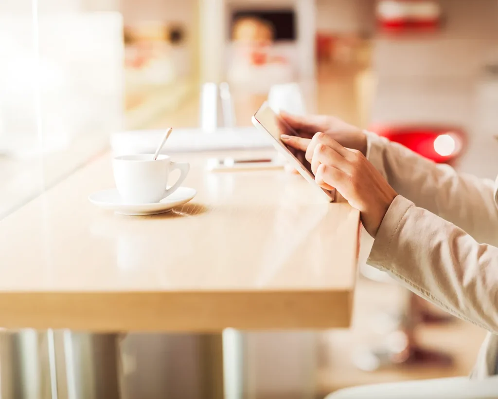 Person using a tablet in a modern café interior, illustrating restaurant website usability, online reservations, and digital hospitality experience
