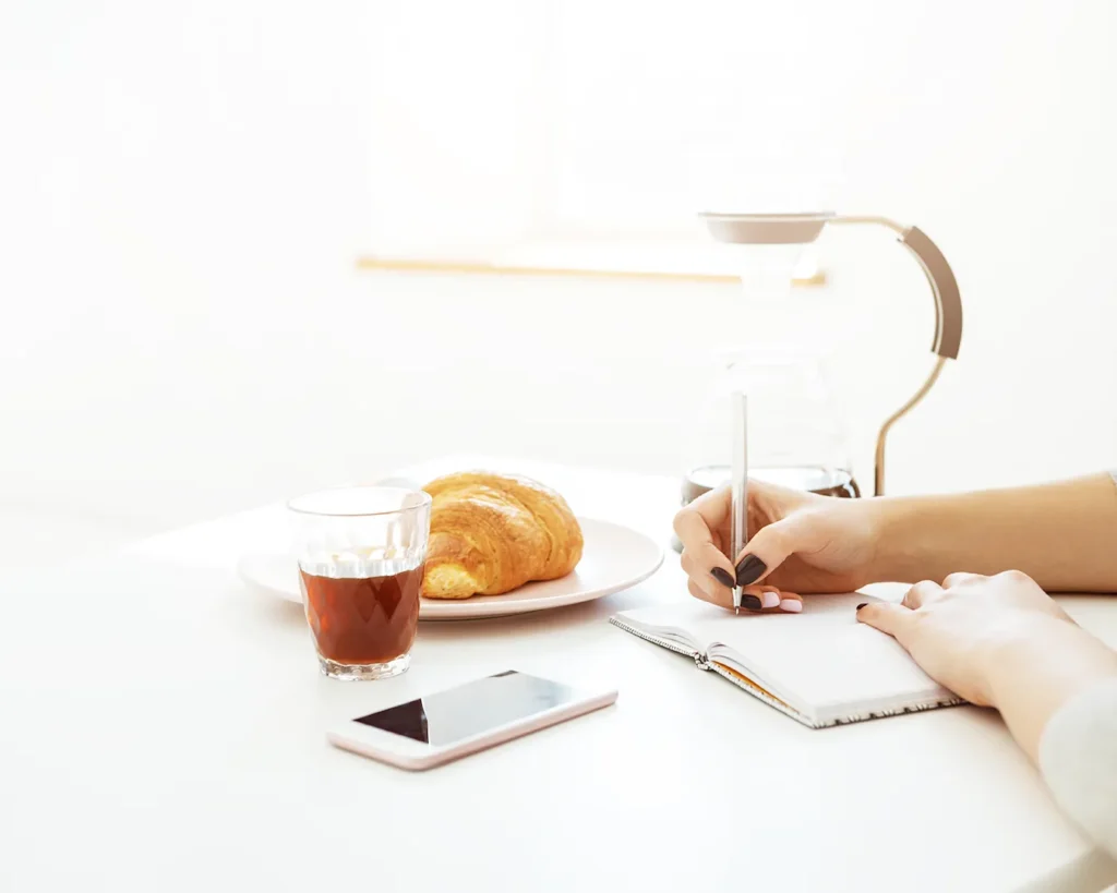 Minimalist cafe table with notebook, coffee, and smartphone for restaurant marketing content planning
