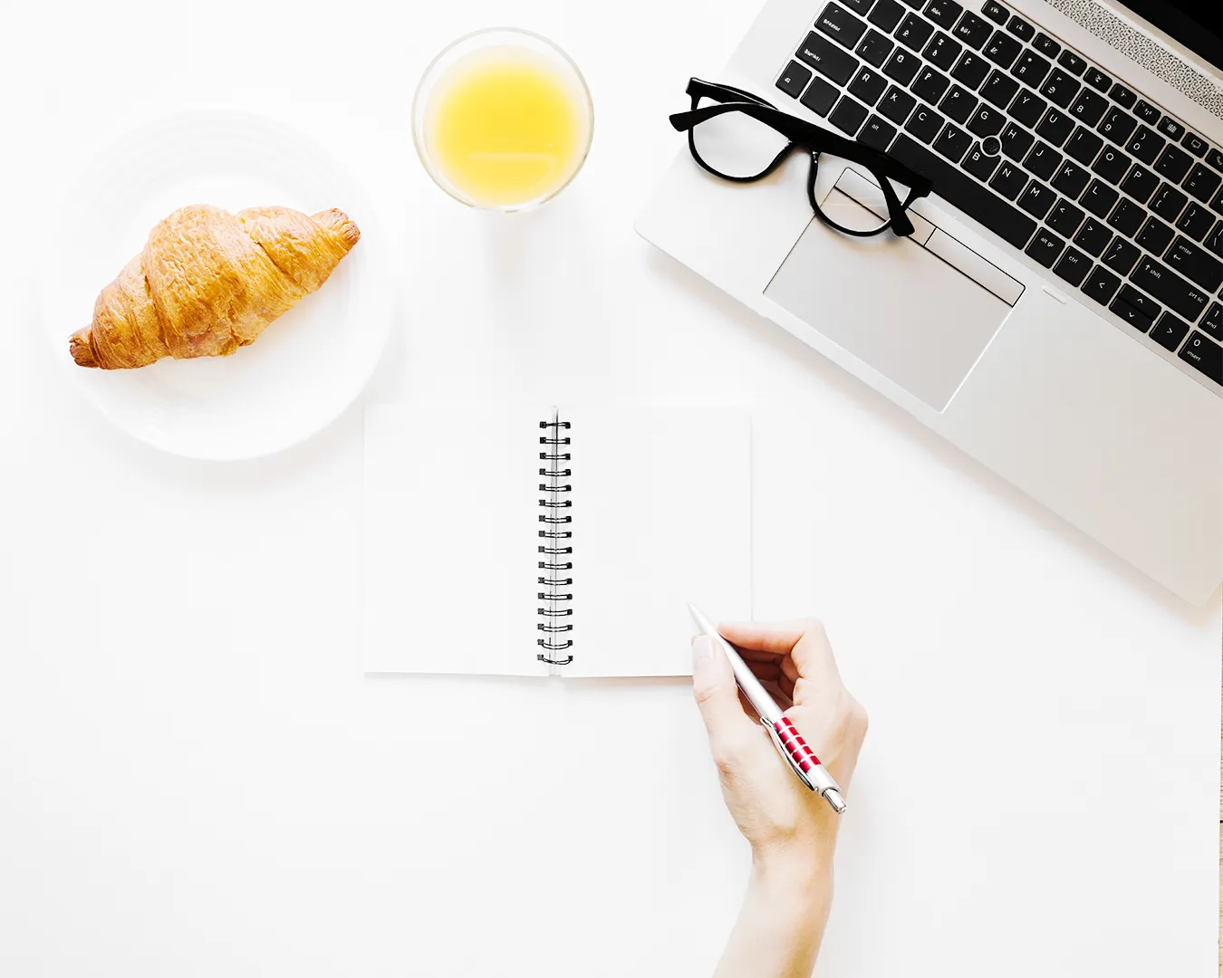 Minimalist restaurant content planning workspace with croissant, tea, notebook, and laptop, symbolizing hospitality storytelling, content strategy, and brand trust building.