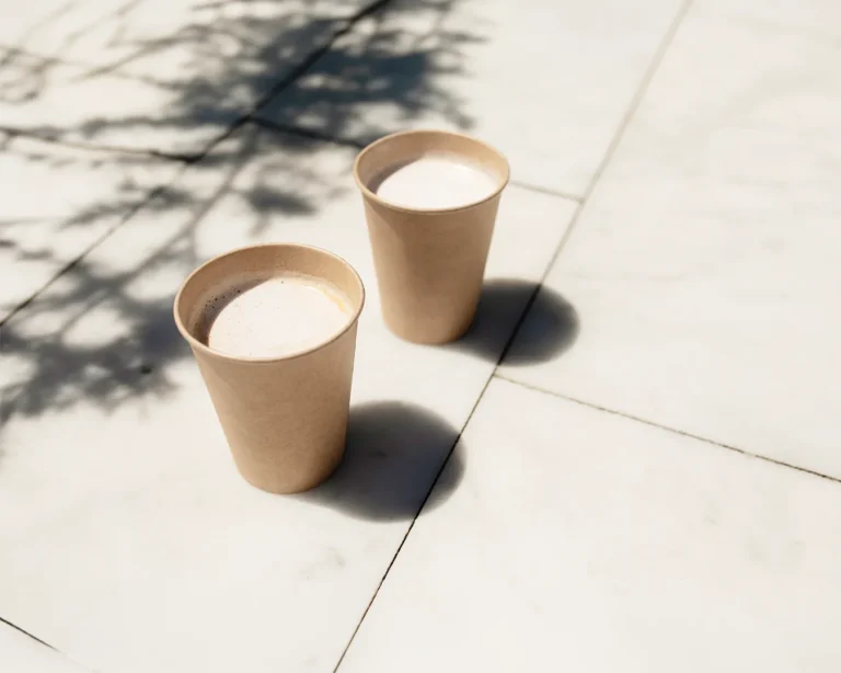 Minimalist takeaway coffee cups on outdoor pavement for restaurant rebranding concept