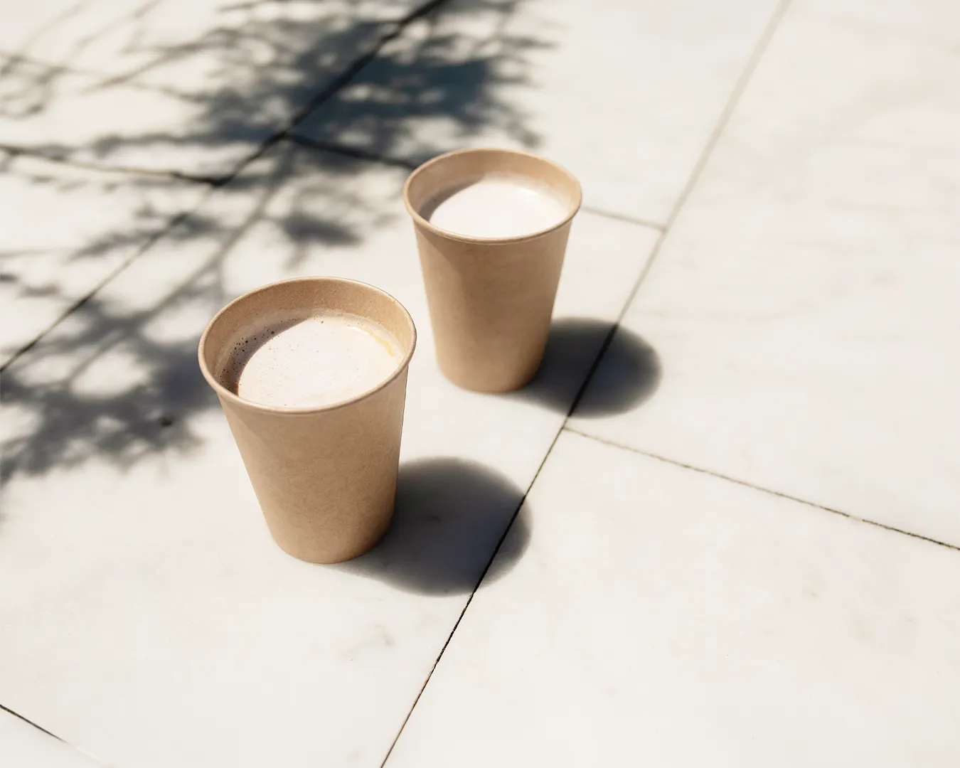 Minimalist takeaway coffee cups on outdoor pavement for restaurant rebranding concept
