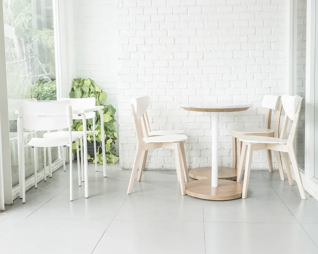 Bright minimalist café interior with white brick walls, wooden tables, and modern dining chairs