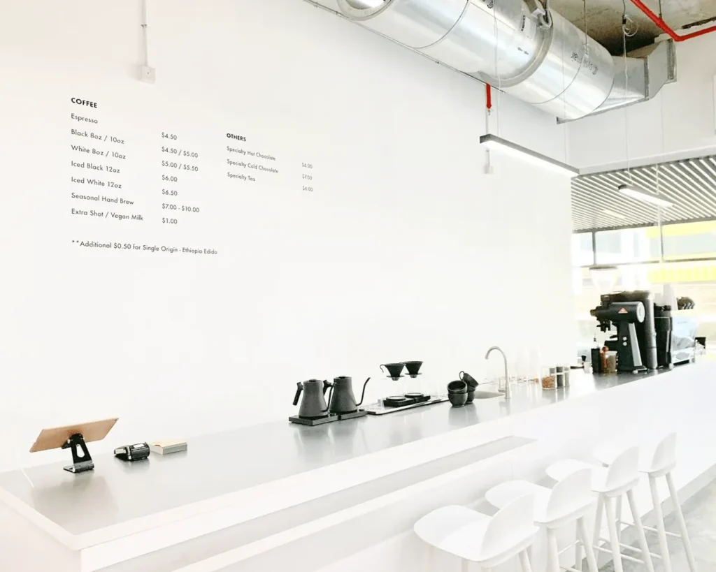Modern white café interior with minimalist menu wall and clean restaurant branding design