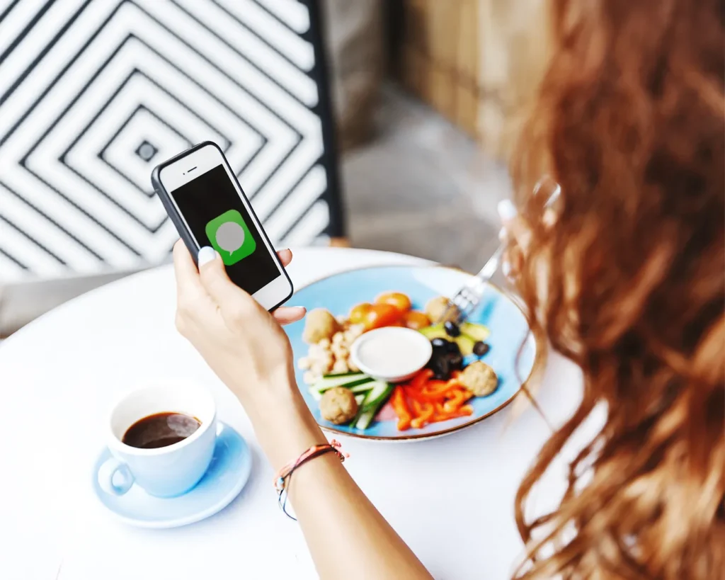 Restaurant customer checking promotional text message while dining in café