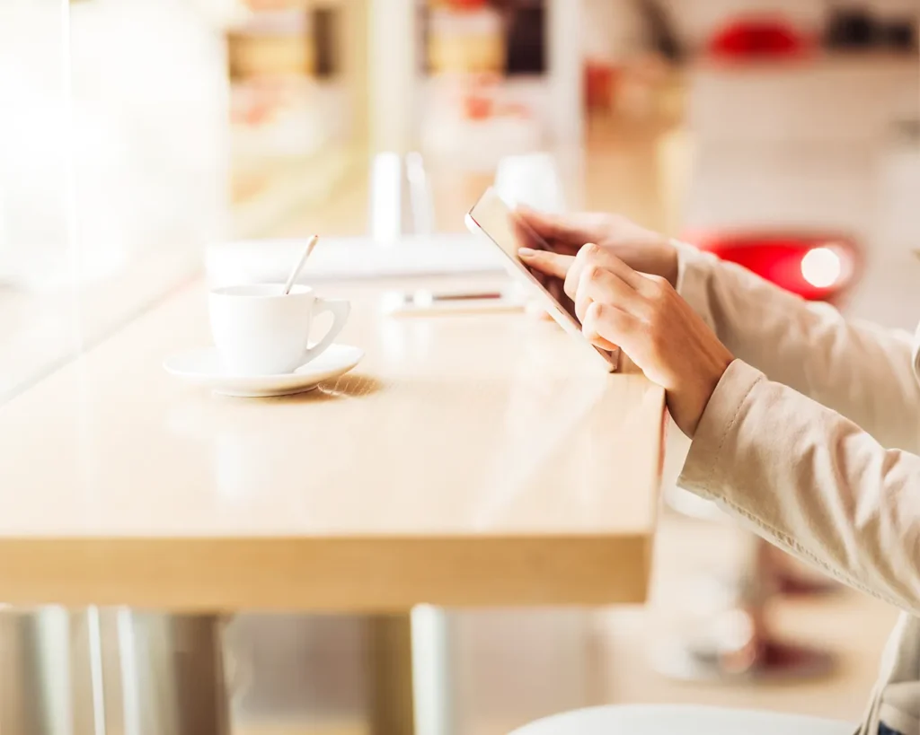 Person using tablet with coffee in bright modern café