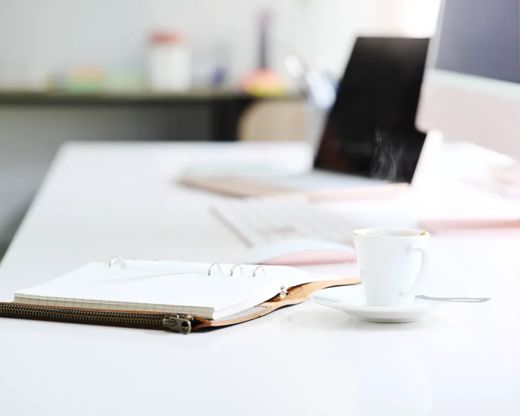 Clean hospitality workspace with notebook, coffee cup, and laptop in soft natural light, representing restaurant marketing strategy, brand transparency, and thoughtful content planning.