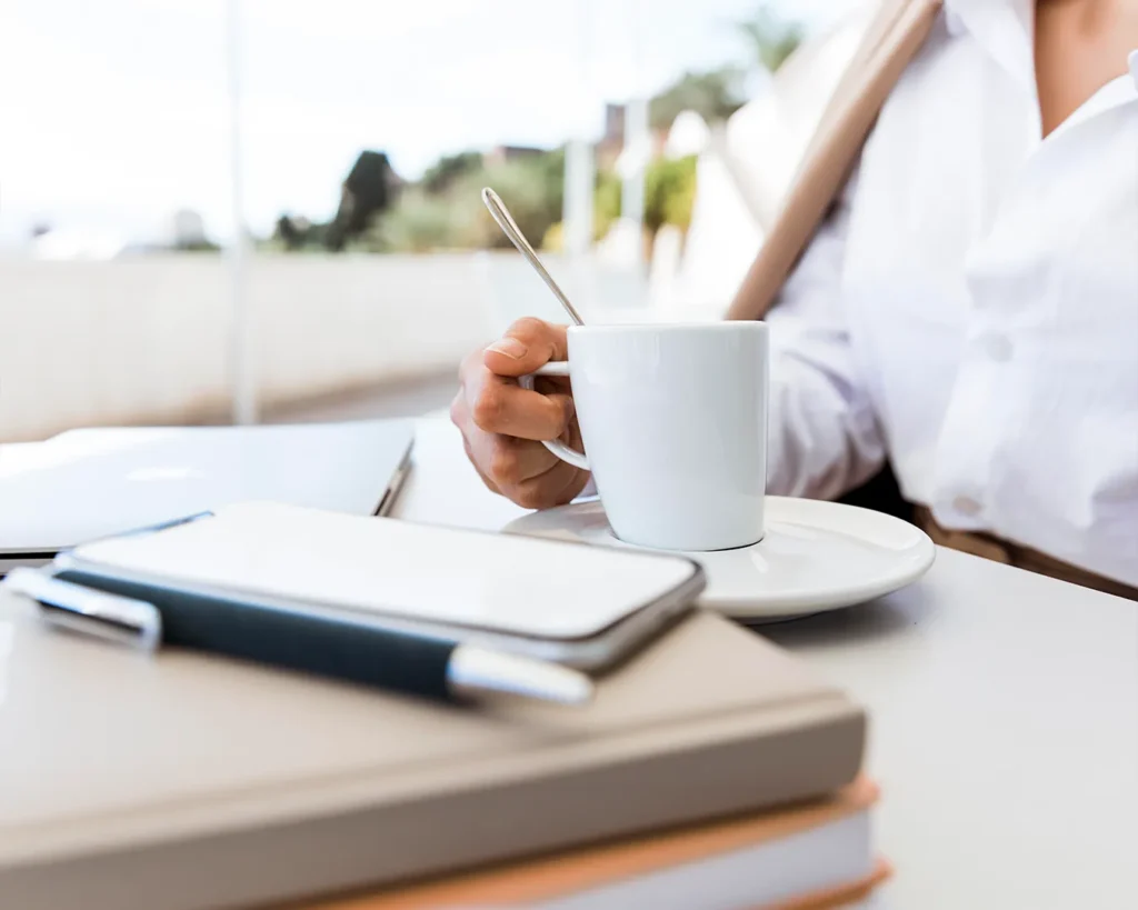 Restaurant marketing planning session with coffee, notebook and mobile device in bright minimalist workspace