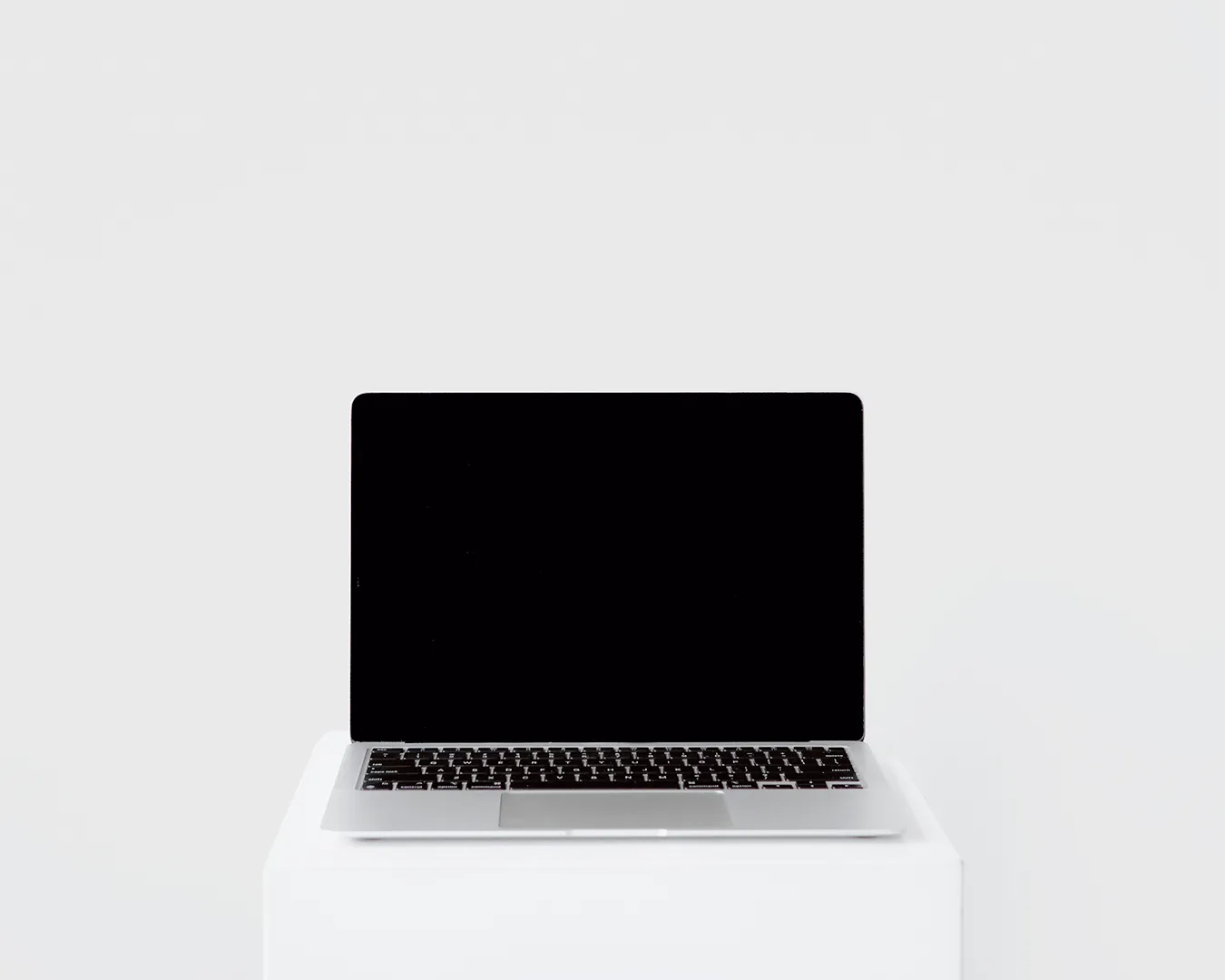 Minimalist laptop on a white pedestal symbolizing restaurant website development, digital launch strategy, and web-first online ordering.