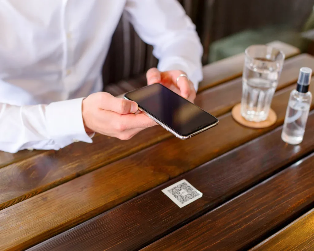 Customer scanning a restaurant QR code with smartphone for web-based loyalty rewards and contactless dining experience.