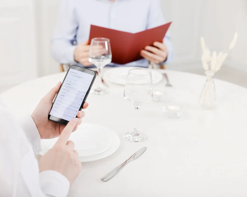Restaurant guests comparing QR code menu on smartphone with a printed menu, highlighting digital ordering and customer dining preferences.